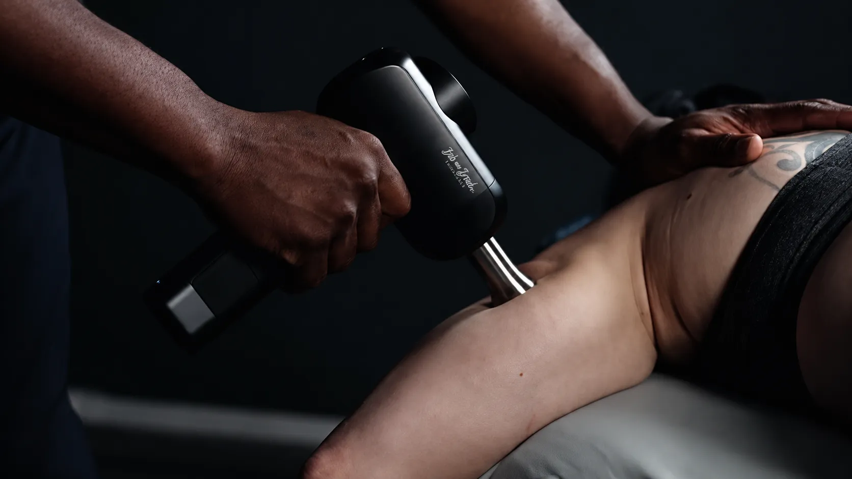 Percussion massage device applied to a hamstring at Hands of Time Wellness for sports recovery and mobility work
