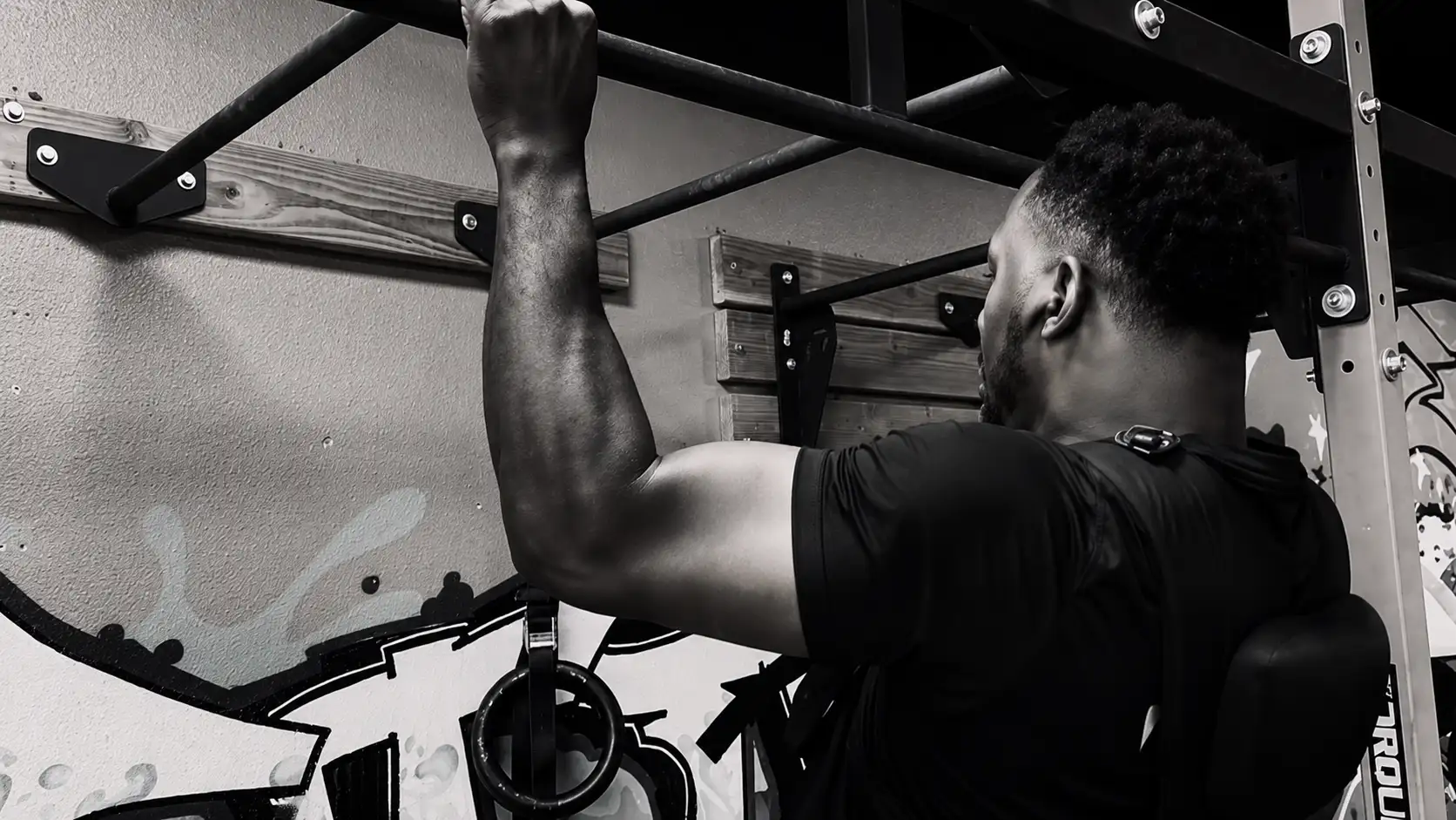 Byron performing a pull-up in a Hands of Time t-shirt on a rig at Mission Accomplish Gym in Kennewick
