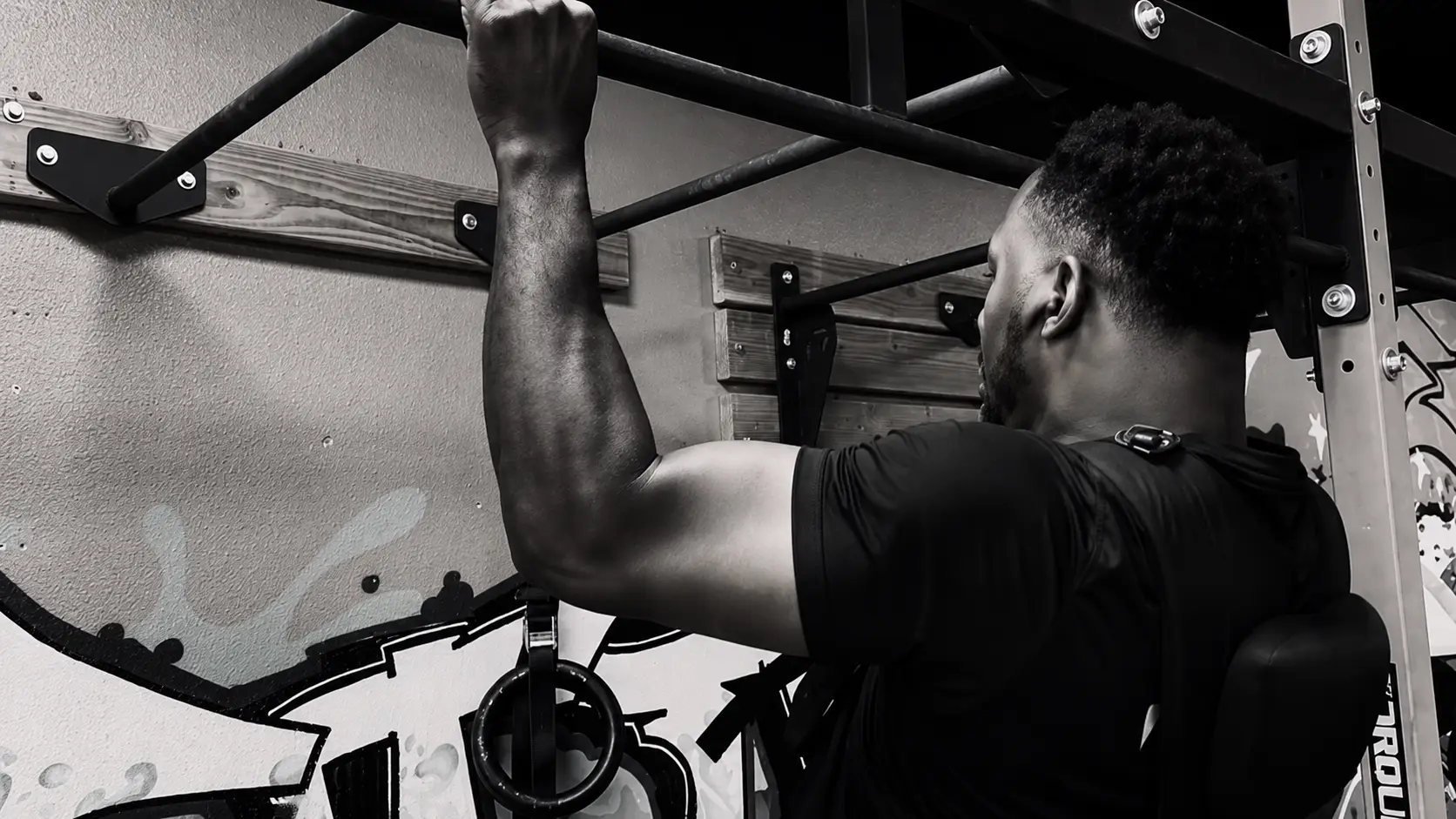 Byron performing a pull-up in a Hands of Time t-shirt on a rig at Mission Accomplish Gym in Kennewick